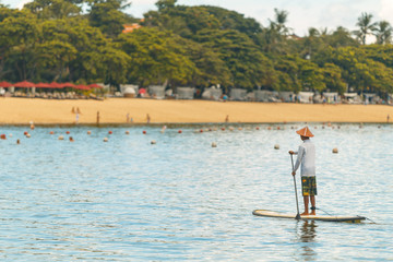 Fototapeta premium Young man floating on a SUP board. The adventure of the sea with blue water on a surfing.