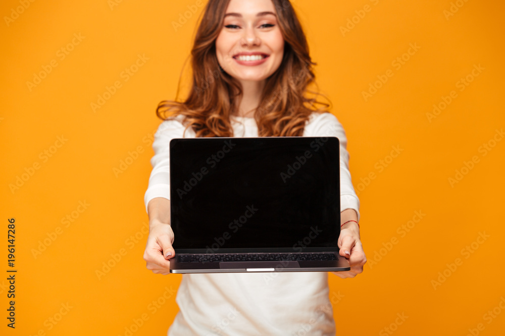 Poster Smiling brunette woman in sweater showing blank laptop computer screen