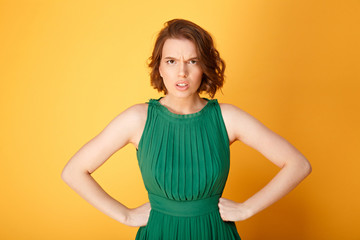 Obraz premium portrait of unsatisfied woman akimbo isolated on orange