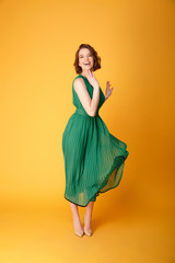 happy young beautiful woman in green dress isolated on orange