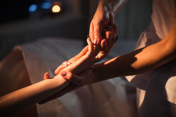 The beautician is massaging the female arm in professional beauty salon. Close-up view. No face.