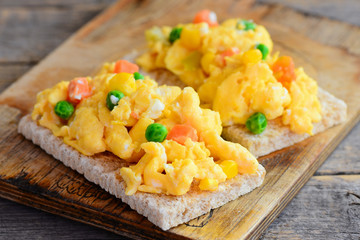 Scrambled eggs with vegetables on crispy bread. Healthy scrambled egg omelet. Easy homemade cooking. Rustic style. Closeup