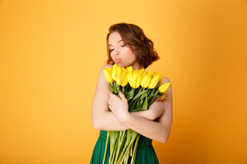portrait of young woman with bouquet of yellow tulips isolated on orange