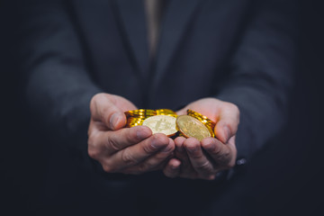 Fototapeta premium Close-up of businessman's hands full of bitcoin sign of coins - cryptocurrency financial trade wealth and business investment and blockchain technology