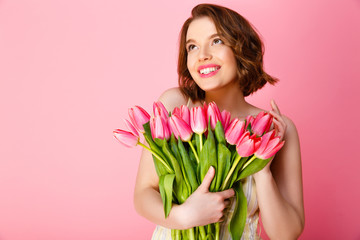 portrait of cheerful woman with bouquet of spring tulips isolated on pink