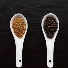 Black and red pepper, set of spices in spoons. Black background