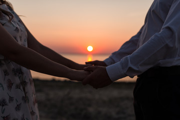 Guy and girl holding their hands on the background of the moon. Sunset