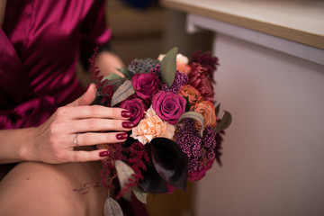 Beautiful wedding bouquet in hands of the bride. Trendy and modern wedding flowers in marsala colors. Prepare for the wedding.