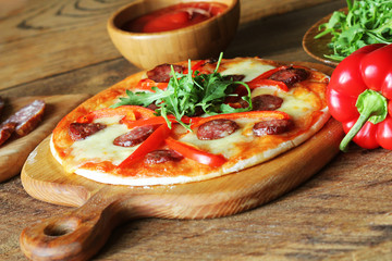 Hot homemade pizza with Pepperoni, paprica, rucola on wooden table
