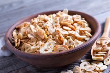 Bowl with dried garlic flakes on wooden background