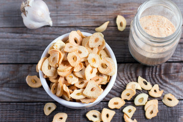 Dried garlic flakes or garlic chips and raw garlic bulb on old wooden background