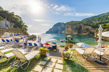 Sunbeds and umbrella on the beach in Corfu Island, Greece. - obrazy, fototapety, plakaty