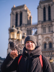 Fototapeta na wymiar Man feeding pigeons in the square in front of the cathedral of Notre Dame