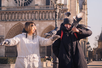 Fototapeta na wymiar Tourists feeding pigeons in the square in front of the cathedral of Notre Dame