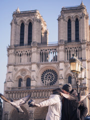 Fototapeta na wymiar Tourists feeding pigeons in the square in front of the cathedral of Notre Dame