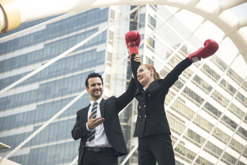 happy businesswoman with boxing gloves on arms raised in victory stands with businessman.concept...