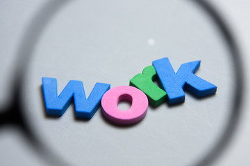 WORK, word written on white background with colorful letters under magnifying glass.