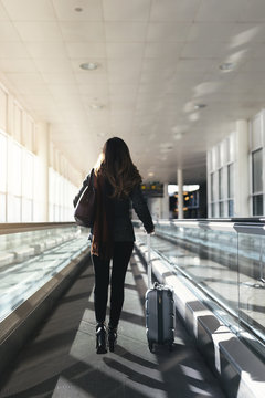Unrecognizable woman walking with suitcase in the airport.