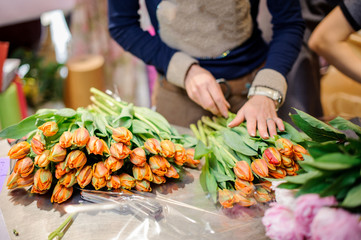 Florist making a bouquet of orange tulips