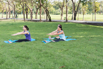 Family practicing yoga in the park outdoor. Concept of healthy lifestyle and relaxation..