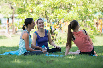 Families with young Russian mother and daughter are talk about exercise and Drink Water. After practice yoga at the park finished. Health and Fitness concept