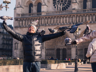 Man feeding pigeons in the square in front of the cathedral of Notre Dame