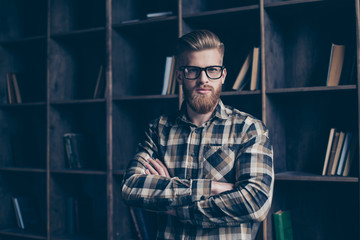 Obraz na płótnie Canvas Portrait of handsome clever brutal serious minded pensive thoughtful planning dreamy journalist standing with crossed arms in casual checkered shirt in front of bookstore