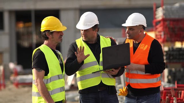 Construction site manager giving instructions using a laptop digital computer