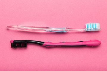 Two toothbrushes on a pink background, close-up.
