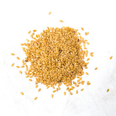 Heap of golden flax seeds on rustic surface top view