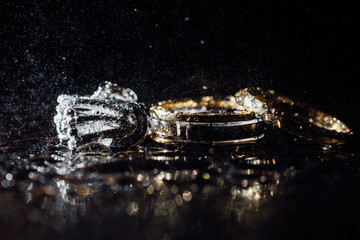 Wedding rings and earrings are wet, with drops. Reflections on the glass are professional.