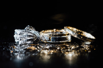 Wedding rings and earrings are wet, with drops. Reflections on the glass are professional.