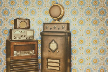Old radio's in front of a retro wallpaper with flower pattern