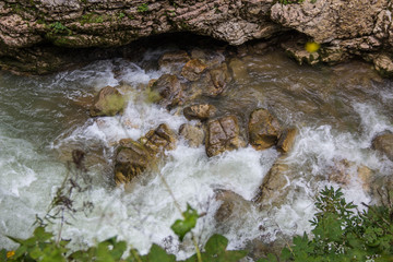 Mountain river flowing through the green forest and many stones