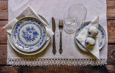 Vintage table setting with china and silver cutlery on the wooden background