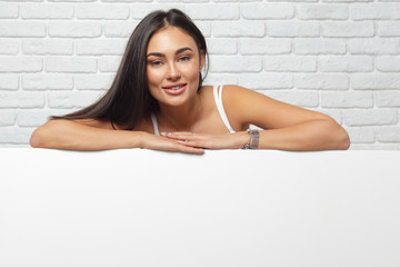 young brunette woman holding large blank white board with copy space