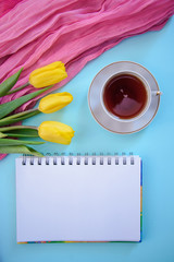 Beautiful romantic picture with notepad, tea and tulips on blue background
