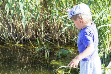 Little boy on the river. A little boy throws pebbles into the river