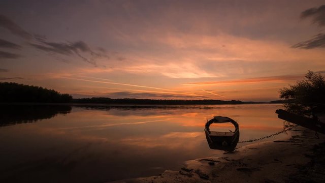calm sunset on calm water with half sunken boat