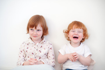 Laughing redhead brother and sister on the white background