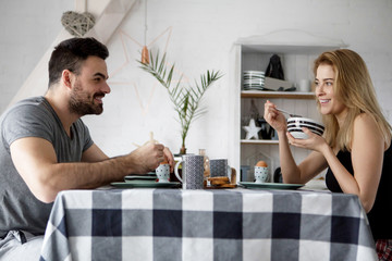 Loving couple sitting at a kitchen table, having a breakfast together