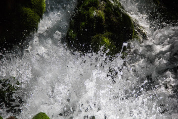 Close up photo of a fresh clean waterfall surrounded by green moss covered rocks