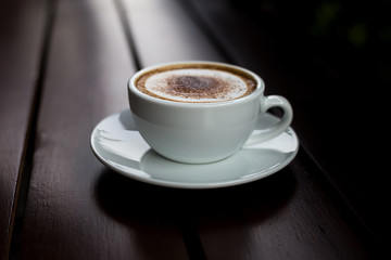 Coffee in a white cup on a wooden table.