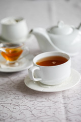 White cup of tea with honey on a white background with teapot. Serving tea. Honey in Saucer.