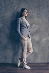 Full-size full-length portrait of cheerful glad confident concentrated dreamy pondering thinking pensive planning office worker keeping hands in pockets  trousers isolated on concrete gray background