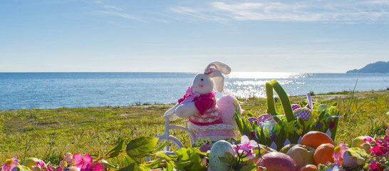Easter bunny and color eggs on the beach by the sea. Spring picnic