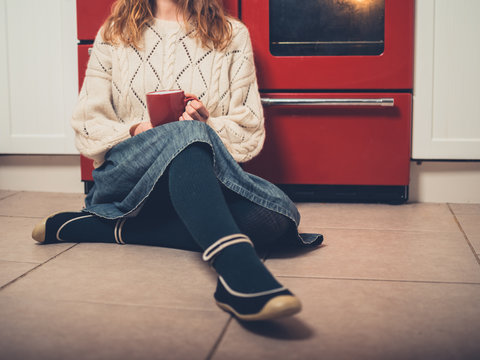 Woman with cup of tea on kitchen floor