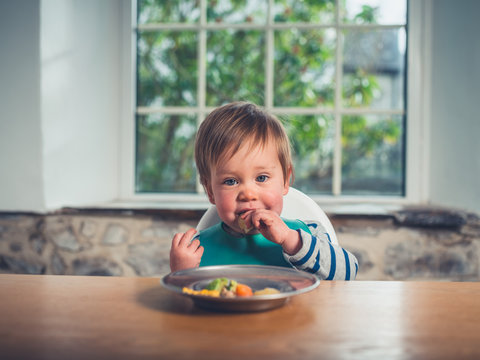 Cute little baby having his dinner at the table