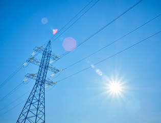 High voltage power lines on the background of blue sky with the sun