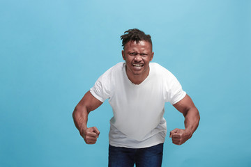 Fototapeta premium The young emotional angry afro man screaming on blue studio background